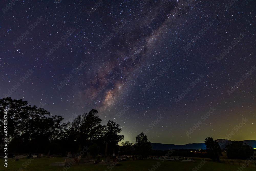 A rural cemetary with the stars and milky way sky shining brightly