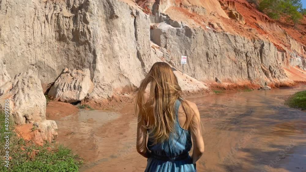 Slowmotion shot. A woman tourist is visiting the red canyon or Fairy stream at the border of desert in the Mui Ne village in southern Vietnam. Shot on a phone Slowmotion shot. A woman tourist is visiting the red canyon or Fairy stream at the border of desert in the Mui Ne village in southern Vietnam. Shot on a phone