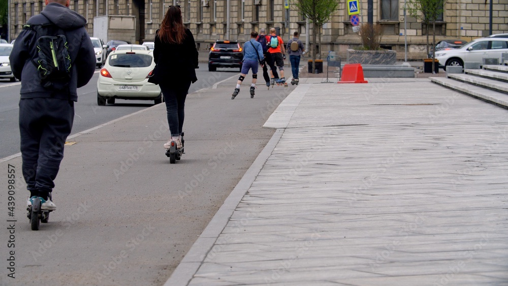 Traffic. Many people ride rollerblades and scooters along the sidewalk. City traffic. Morning with a big city, people go to work Traffic. Many people ride rollerblades and scooters along the sidewalk. City traffic. Morning with a big city, people go to work