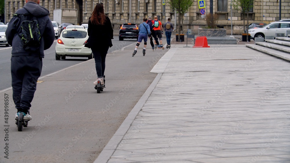 Traffic. Many people ride rollerblades and scooters along the sidewalk. City traffic. Morning with a big city, people go to work