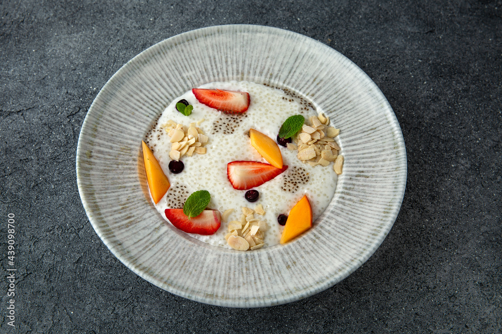 Healthy vegetarian wholesome breakfast porridge with berries, fruits and chia seeds. Ready menu for the restaurant. Neutral gray blue textured background