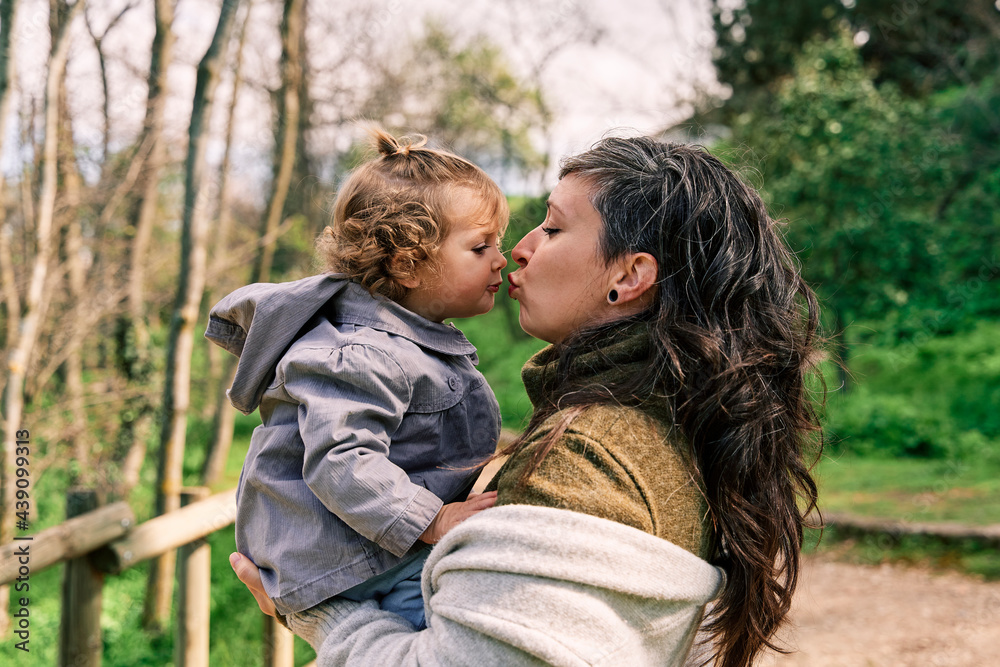young mother holding her daughter in her arms and kissing each other