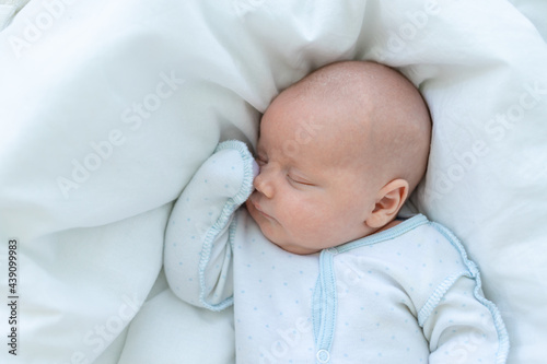 newborn baby boy sleeps seven days in a cot at home on a cotton bed, close-up