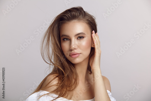 Young woman in stylish dress looks at camera in studio