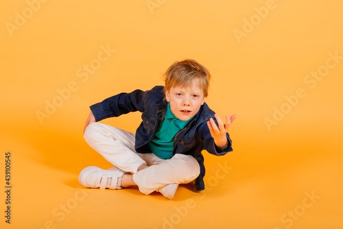 Grimacing emotional redhead fasion boy posing in yellow studio