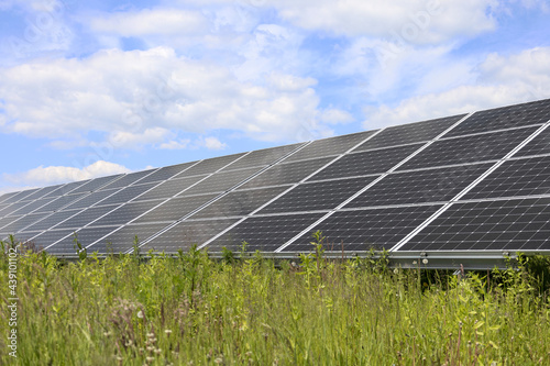 Solar panels on green grass and sky background. Solar power plant. Blue solar panels. Alternative source of electricity. Solar farm.