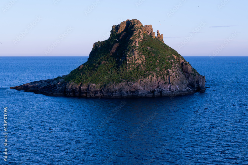 Evening view of Thatcher rock, Torquay, Torbay, Devon England. Rock formation in the ocean. Sunset low light image.