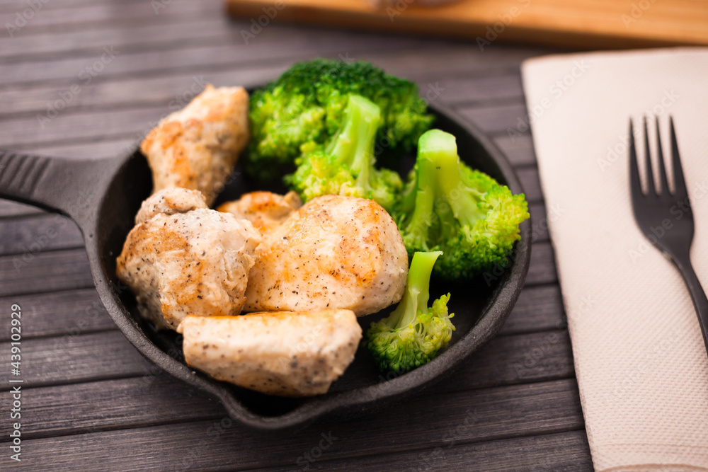 pieces of fried chicken breast with boiled broccoli egg in cast iron portioned skillet