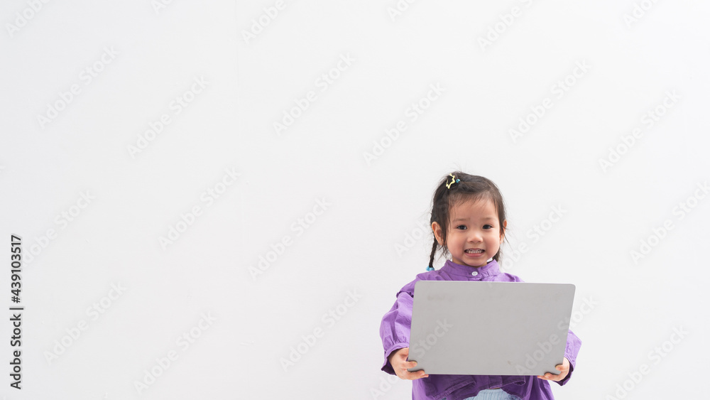 Portrait of a smiling little girl in purple dress holding laptop computer isolated over white background Portrait of a smiling little girl in purple dress holding laptop computer isolated over white background