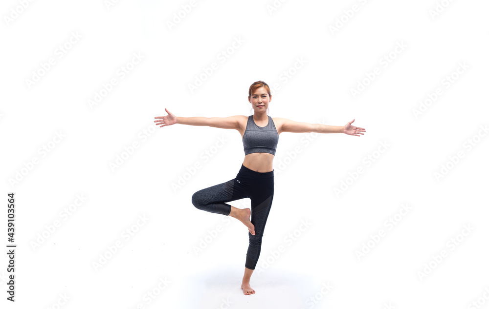 Young woman in grey sport wears doing yoga on leg in studio white background. Concept of home exercise. Yoga time at home.
