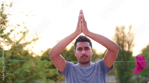 Healthy young man doing stretching exercise on green grass at park. Yoga day concept © thala bhula