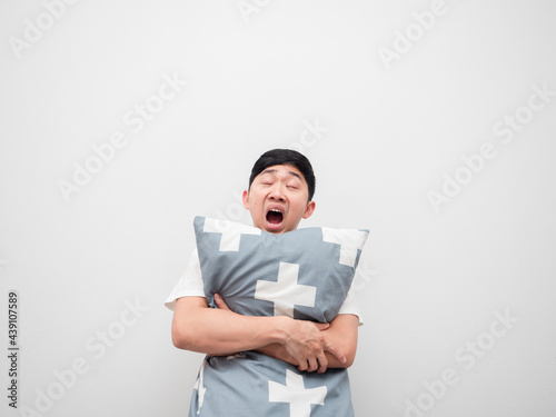 Asian sleepy man yawn and hug pillow on white background lazy concept