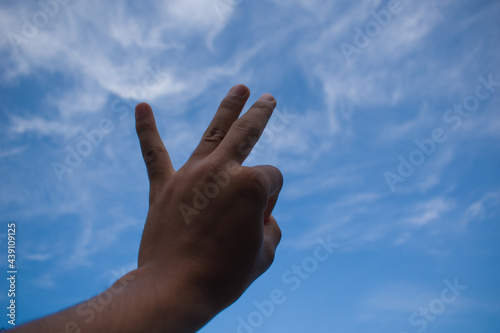 Ok gesture with left hand to dark blue sky