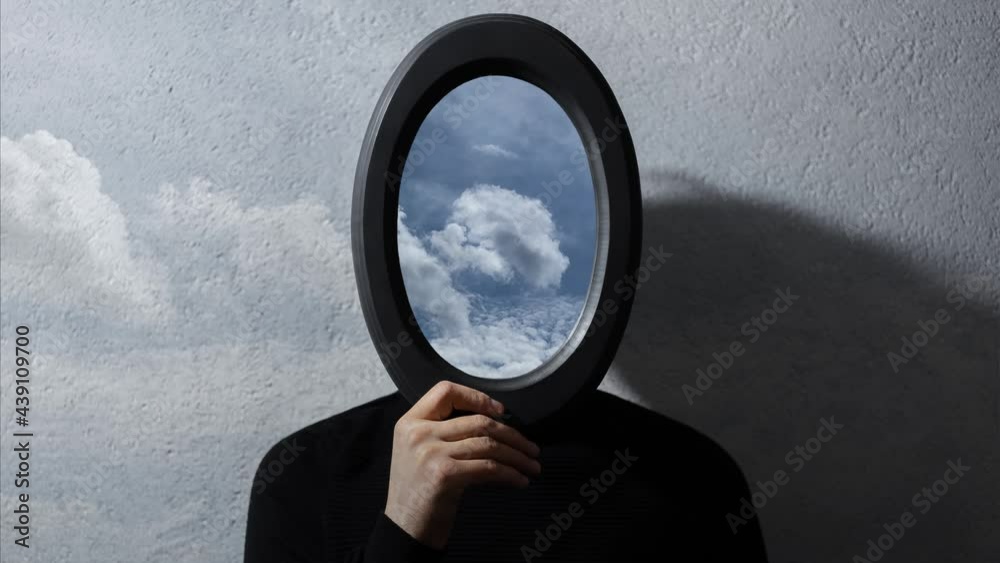 Contemporary artwork video collage. Young man holding black frame on face with beautiful time lapse of cloudy sky.