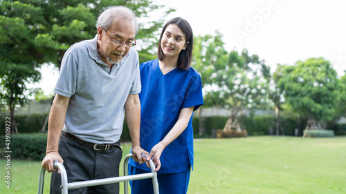 Asian Senior older man walk in public park with carer nurse's support. © Kawee