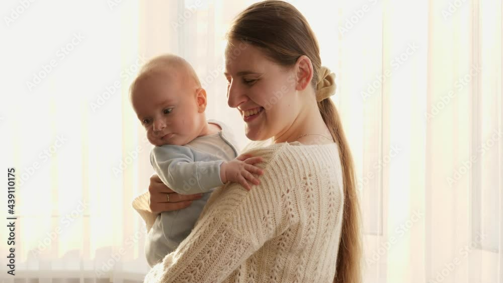 Young mother hugging and smiling at her little baby son in sunset light. Concept of family happiness and parenting Young mother hugging and smiling at her little baby son in sunset light. Concept of family happiness and parenting