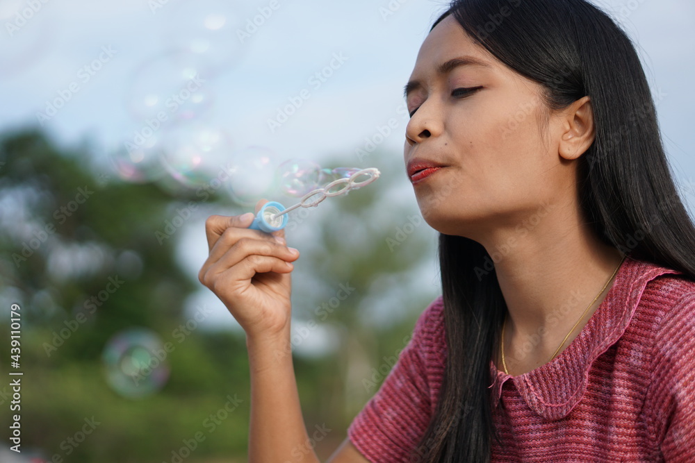Asian woman blowing soap bubbles every green grass background