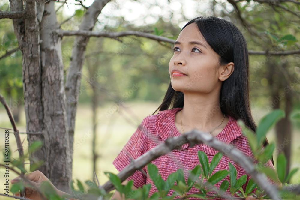 Asian woman happily exploring and walking into the trees Asian woman happily exploring and walking into the trees