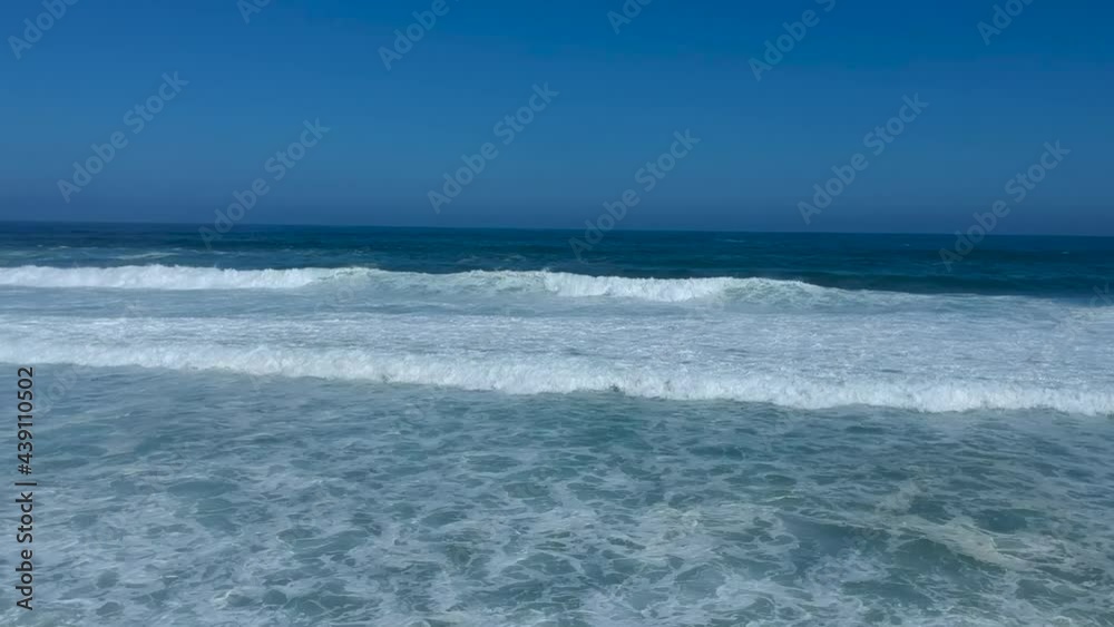 White waves breaking on a beach with turquoise skies no clouds, crystal clear day camera is stationary above the waves Aerial Video White waves breaking on a beach with turquoise skies no clouds, crystal clear day camera is stationary above the waves Aerial Video