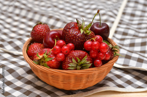 different summer berries in a basket on the kitchen table close-up