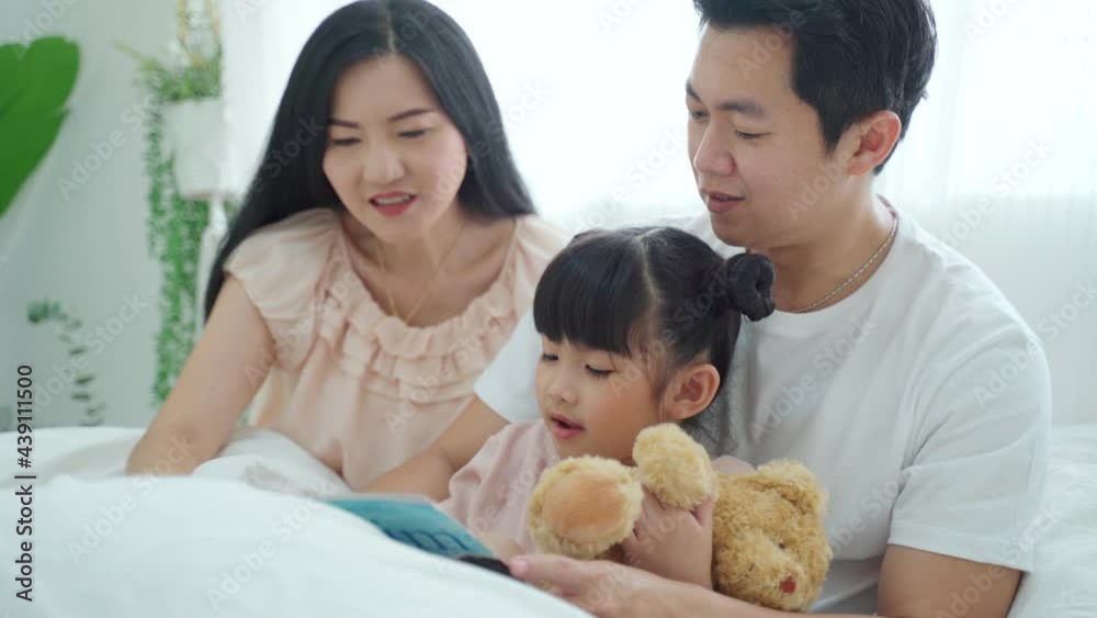 Asian family parent read storytale book to young daughter in bedroom. Asian family parent read storytale book to young daughter in bedroom.