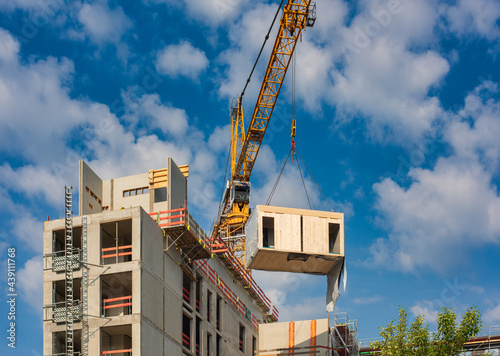 Fotografering Crane lifting a wooden building module to its position in the structure