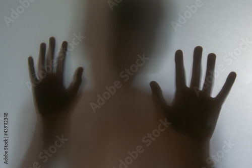 Reflection of shadows of children hands on frosted glass, blur