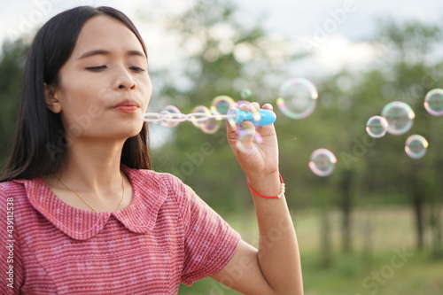 Asian woman blowing soap bubbles every green grass background