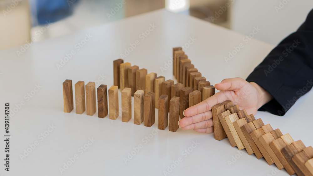 Businessman protecting the wooden block, construction business risk concept.