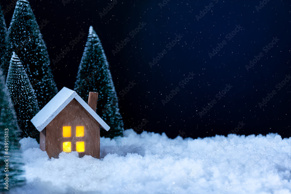 New year and Christmas background. There are artificial  Christmas trees, figurine of wooden house and artificial snow on the photography. Copy space. Horizontal orientation.