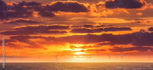 Renewable green electricity wind power generation offshore. Sunrise at decarbonization industry windmills business for regenerative energies. Clean energy renewables preventing climate change