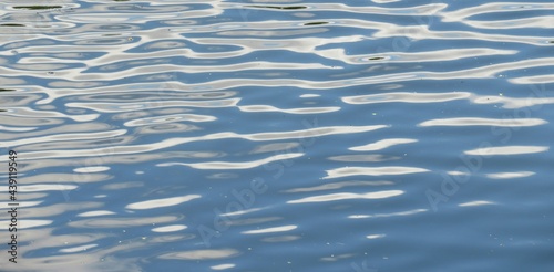 Closeup of light blue river water surface with white spots, natural water background