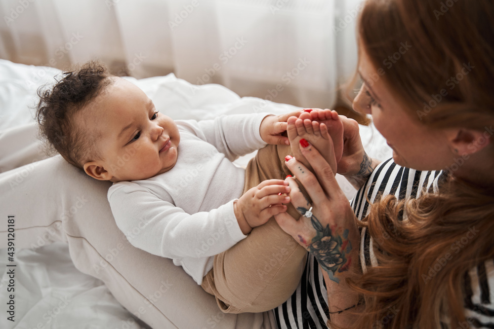 Woman looking at her child and touching her baby's legs Woman looking at her child and touching her baby's legs