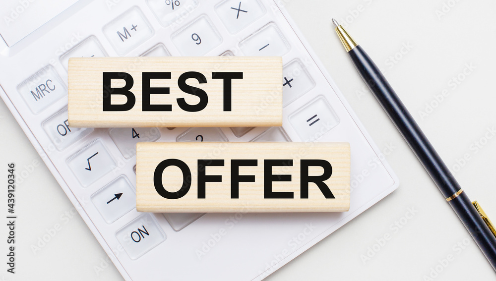Wooden blocks with the text BEST OFFER lie on a light background on a white calculator. Nearby is a black handle. Business concept Wooden blocks with the text BEST OFFER lie on a light background on a white calculator. Nearby is a black handle. Business concept