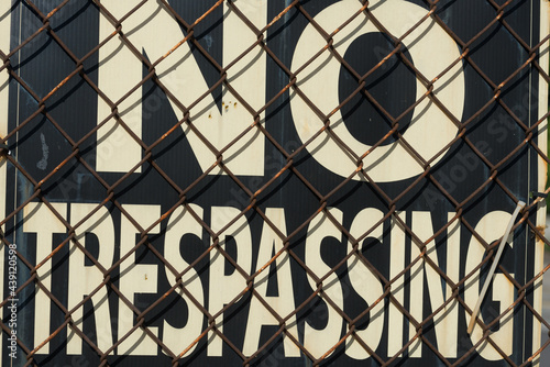 old no trespassing sign behind a rusty chain link fence