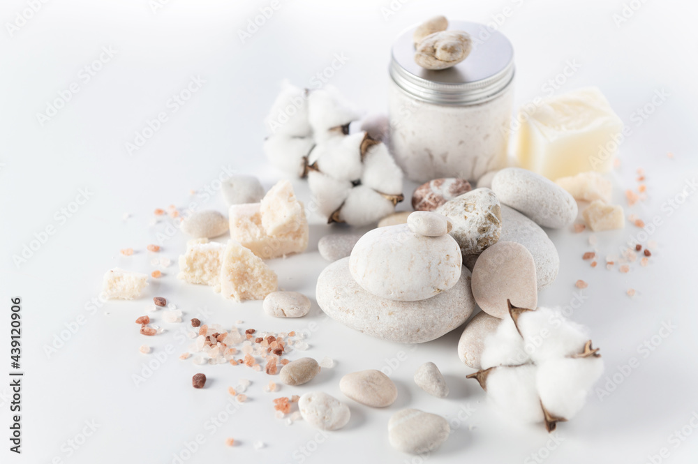 body and soul care, round stones, sea salt, salt soap, body peeling cream, cotton flowers on a white background body and soul care, round stones, sea salt, salt soap, body peeling cream, cotton flowers on a white background