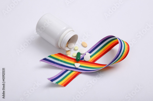 Pills bottle with LGBT rainbow ribbon pride tape symbol on white background.