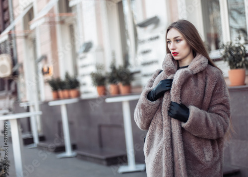 Fashion woman in a luxurious fur coat in the city