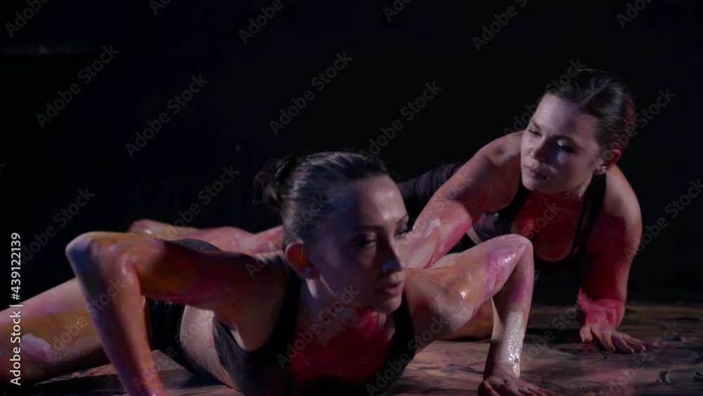 A woman artist with her body in a dance creates a masterpiece with paints on the floor A woman artist with her body in a dance creates a masterpiece with paints on the floor