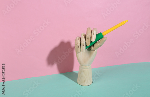 Wooden hand holding toy screwdriver on blue pink pastel background. Trendy shadow. Concept art. Minimalism. Creative layout