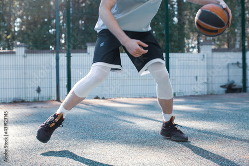Professional male american basketball player with ball dribbling on court outdoors, close up cropped photo