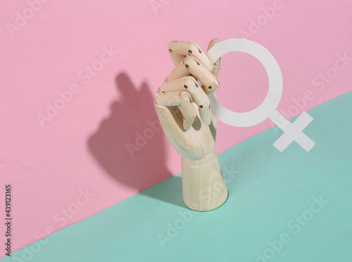 Wooden hand holds venus symbol on pink blue pastel background