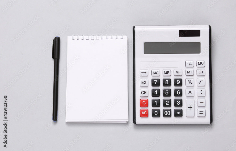 Calculator and notebook on gray background. Top view. Flat lay Calculator and notebook on gray background. Top view. Flat lay