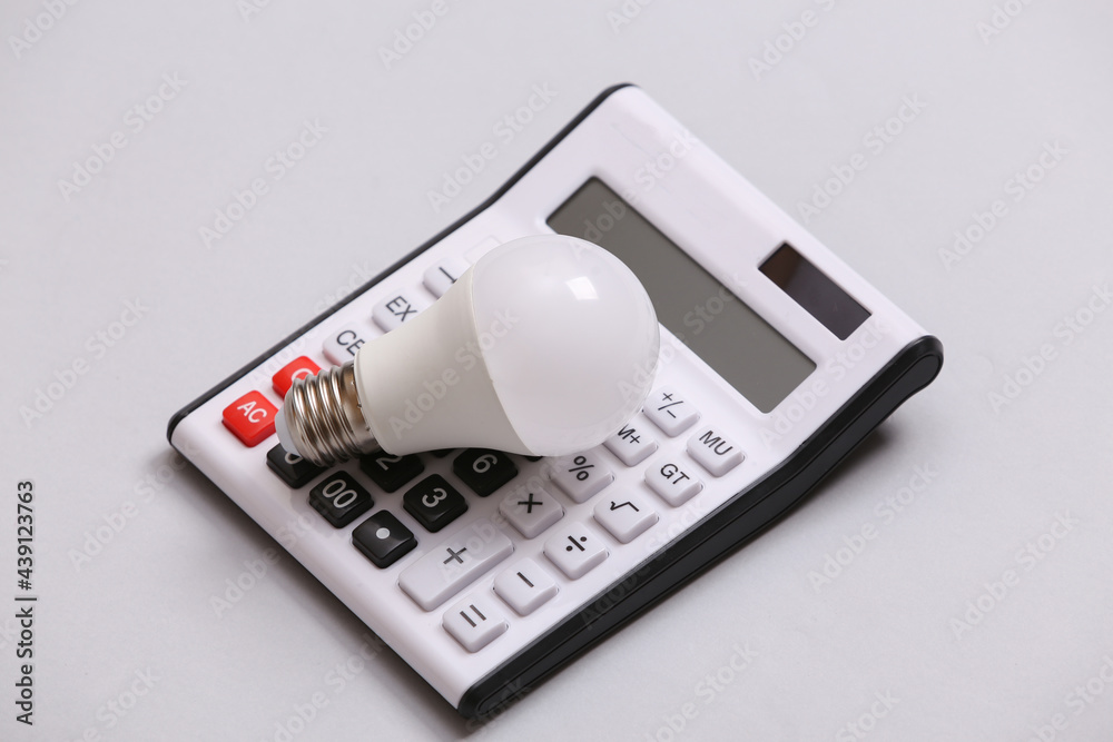 Calculator and led light bulb on gray background. Calculator and led light bulb on gray background.