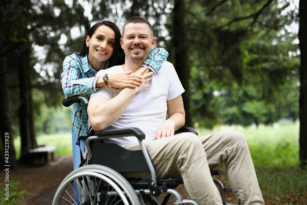 Young woman hugs disabled man in wheelchair on walk in park Young woman hugs disabled man in wheelchair on walk in park