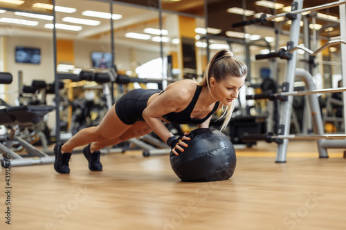 Fototapeta Naklejka Na Ścianę i Meble -  Slim fit Woman push ups with medicine ball in the gym. Functional training