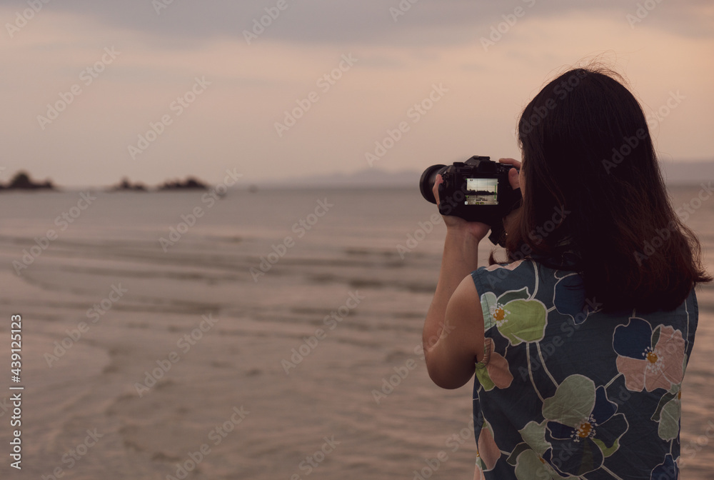portrait of young woman using camera to take picture of the beach during summer vacation portrait of young woman using camera to take picture of the beach during summer vacation