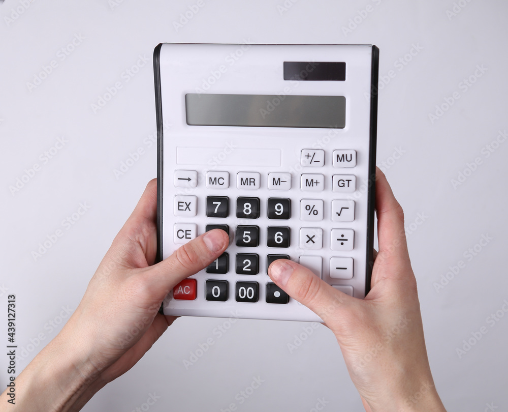 Hands using calculator on gray background Hands using calculator on gray background