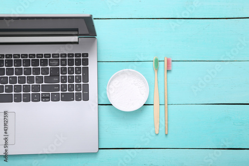 Laptop, Eco bamboo toothbrushes with tooth powder on wooden table. Top view