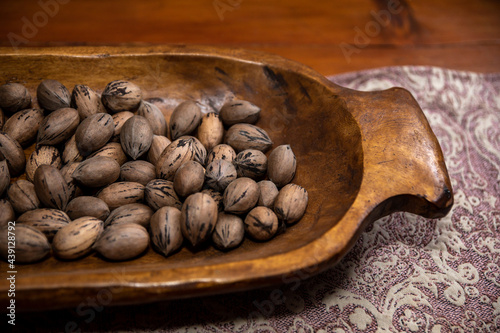 Raw in shell whole Pecan nuts in a wooden bowl on a wood table photo